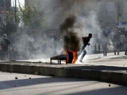 Protestantes palestinos arrojan llantas contra autoridades israelíes; la escalada de violencia entre ambas naciones va en aumento. EFE / A. Al Hashlamoun