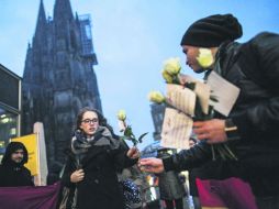 Un miembro de la asociación germano-tunecina entrega una rosa a una mujer fuera de la estación de tren de Colonia. EFE /