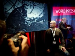 Warren Richardson posa para las cámaras mientras al fondo se proyecta su fotografía ganadora. AFP / K. van Weel