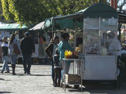Clientes pasean por la Plaza Juan Pablo II y visitan los puestos de frituras y otros, en el Centro zapopano. EL INFORMADOR / F. Atilano