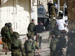 Soldados resguardan el lugar de los hechos mientras personal médico retira el cadáver del palestino. EFE / A. Al Hashlamoun