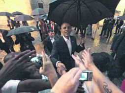 Bajo una pertinaz lluvia, Barack Obama recorrió a pie varias calles y saludó a quienes esperaban afuera de la catedral de La Habana. SUN /