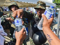 Militares reparten botellas de agua potable a los damnificados; surtir del vital líquido a la población es primordial. AFP / L. Acosta