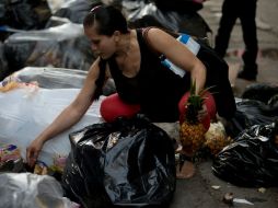 Una mujer busca alimentos entre los desechos de un supermercado. La escasez y el desabastecimiento afectan al país. AP / F. Llano