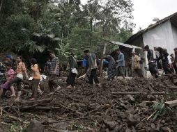 Varias personas son trasladadas a un refugio en medio de un camino severamente dañado por el agua. AP /