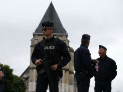 Varios policías vigilan los alrededores de la iglesia de Saint Etienne, donde dos islamistas ayer tomaron rehenes. EFE /  I. Langsdon