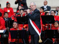 El presidente de Perú toca la flauta con la orquesta sinfónica infantil en el patio del Palacio de Gobierno. AFP / L. González