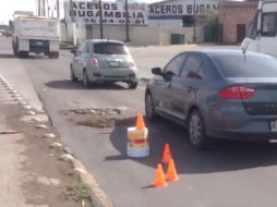 Raúl tapó con piedras, tierra y pasto unos socavones que se encuentran en el retorno de Bugambilias hacia Guadalajara. TWITTER / @AmossPetFood