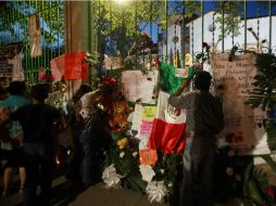 Personas cuelgan flores y mensajes afuera de la casa de Juan Gabriel. EFE / M. Guzmán