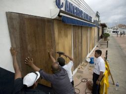 Trabajadores protegen establecimientos ante la inminente llegada del meteoro a Cabo San Lucas. AP / E. Verdugo