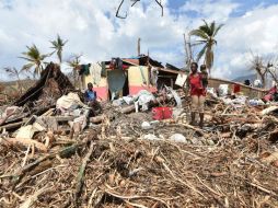 Un grupo de personas yace frente a los restos de sus casas destruidas tras el paso del huracán 'Matthew'. AFP / H. Retamal