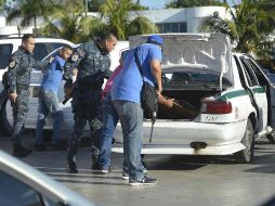 Policías estatales y federales catearon vehículos tras el ataque a varios edificios públicos en la zona Centro de Cancún. EFE / A. Cupul