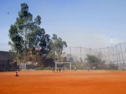 Una densa nube de humo tóxico envuelve el patio de juegos, en donde los pequeños tratan de divertirse a pesar de todo. EFE / J. Martorell