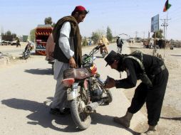 Oficiales de seguridad afgano registran a varios ciudadanos en un puesto de control en Helmand. EFE / W. Yar