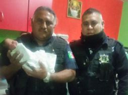 Los oficiales Rogelio (izquierda) y Carlos con el pequeño recién nacido. ESPECIAL / Policía Tlajomulco