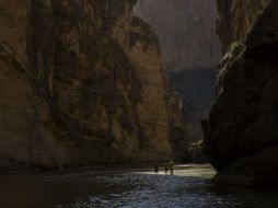 Turistas caminan sobre las aguas del Río Bravo, a través del Cañón Santa Elena, con México a la izquierda y EU a la derecha. AP / R. Abd