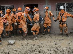 Bomberos y voluntarios trabajan todo el día en medio de un paisaje desolado y sepultado por el lodo. AFP / L. Robayo