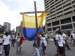 Andrés Ramírez salió a marchar levantando una cruz de casi dos metros de alto envuelta en una bandera venezolana. AFP / J. Barreto