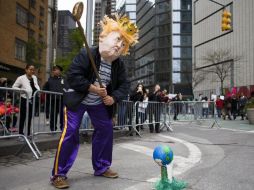 Un hombre disfrazado de Trump apareció con un palo de golf haciendo que golpeaba a la Tierra como pelota. EFE / J. Lane