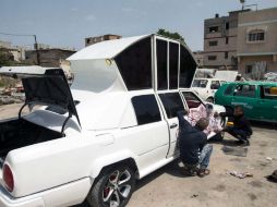 En su pequeño taller mecánico, un grupo de hombres trabaja ensamblando piezas de cinco coches sobre un Mercedes. AFP / M. Hams