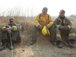 Tres bomberos exhaustos, quienes comenzaron labores a las 04:00 horas, toman un descanso de media hora antes de volver a trabajar. EL INFORMADOR / G. Gallo
