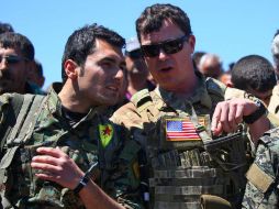 Soldado de las las Unidades de Defensa Popular habla con un oficial estadounidense. AFP / D. Souleiman