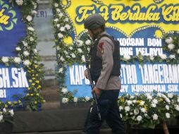 Un policía indonesio camina junto a coronas de flores colocadas en una terminal de autobuses en Yakarta. EFE / A. Weda