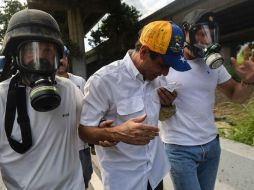 Capriles tuvo que ser auxiliado por sus guardaespaldas para salir del lugar. AFP / L. Robayo