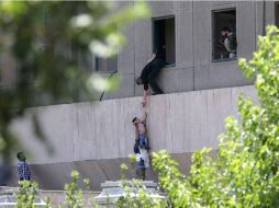 Policías iraníes ayudan a escapar a civiles después de que varios hombres armados irrumpieran en el Parlamento. AFP / O. Vahabzadeh