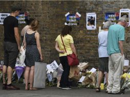 Varias personas observan los mensajes de apoyo, flores y velas dejadas en el lugar del ataque en Finsbury Park. EFE / A. Rain