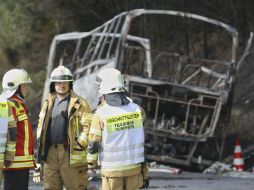 Bomberos trabajan junto a los restos calcinados de un autobús en la carretera A9, donde ocurrió el choque. EFE / E. Fricke