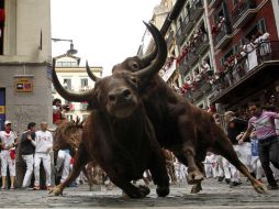 Dos toros de la ganadería de Jandilla resbalan en la curva de Mercaderes durante el quinto encierro de los Sanfermines. EFE / V. López