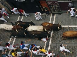 Toros de la ganadería de Núñez del Cuvillo pisan a un mozo a su paso por la calle Estafeta. EFE / P. Urdíroz