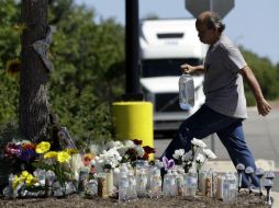 Un hombre deja una botella de agua como parte de un homenaje cerca del sitio donde el tráiler de migrantes fue descubierto. AP / E. Gay