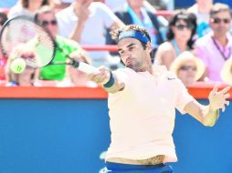 Roger Federer, quien chocará en Octavos de Final con el español David Ferrer, responde una bola al canadiense Peter Polansky. AFP /