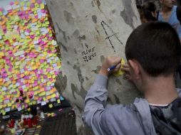 Un niño escribe una nota para dejarla junto a las centenares que hay colgadas en una caseta de Las Ramblas como muestra de apoyo. EFE / M. Pérez