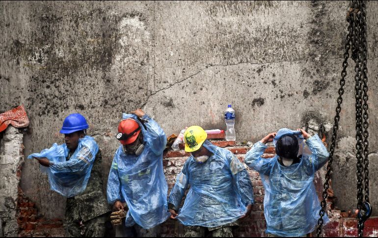 Rescatistas se colocan impermeables para seguir con la búsqueda de sobrevivientes. AFP/R. Schemidt
