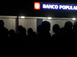 Puertorriqueños hacen fila para un cajero automático en la oscuridad luego de que la mayor parte de la isla se ha visto privada de suministro eléctrico.