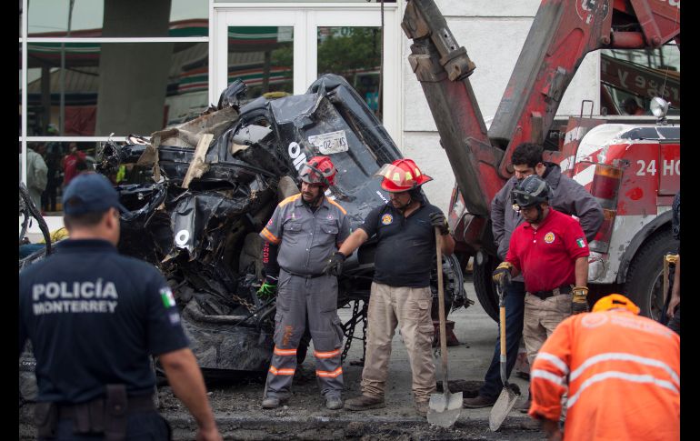 Bomberos y elementos de Protección Civil recuperan el vehículo que cayó en el socavón, en el cual viajaban cinco personas. EFE