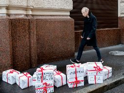 An opposition activist wearing a rubber mask depicting Russian Presid - An opposition activist wearing a rubber mask depicting Russian President Vladimir Putin walks past gift boxes with lettering reading 