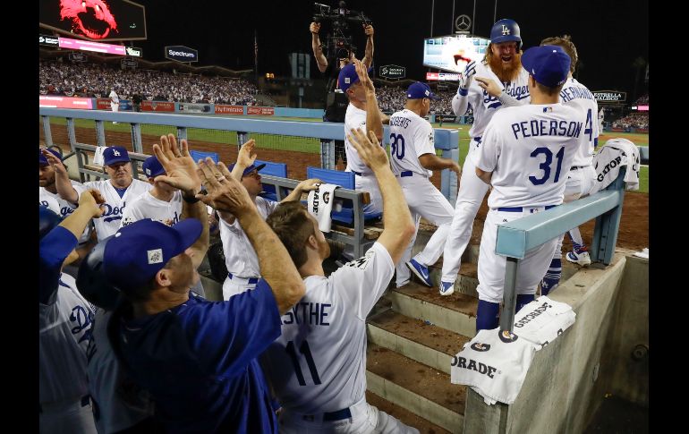 Los jugadores de los Dodgers celebran a Justin Turner después de anotar la segunda carrera en el primer juego. AP / M. Slocum