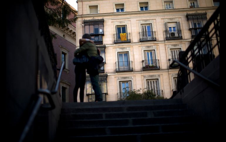 Personas se abrazan frente a un edificio con una bandera de la independencia de Cataluña, en Madrid. AP/F. Seco