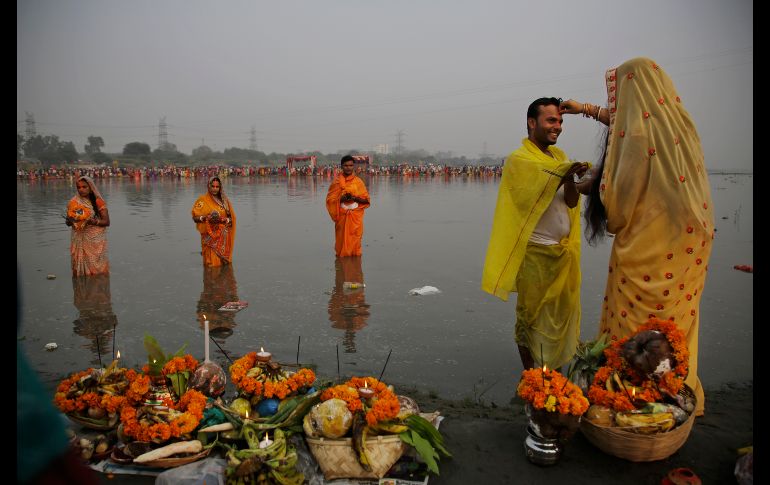 Una hindú coloca polvo de color en la frente de su esposo en el río Yamuna, mientras realizan rituales del festival 