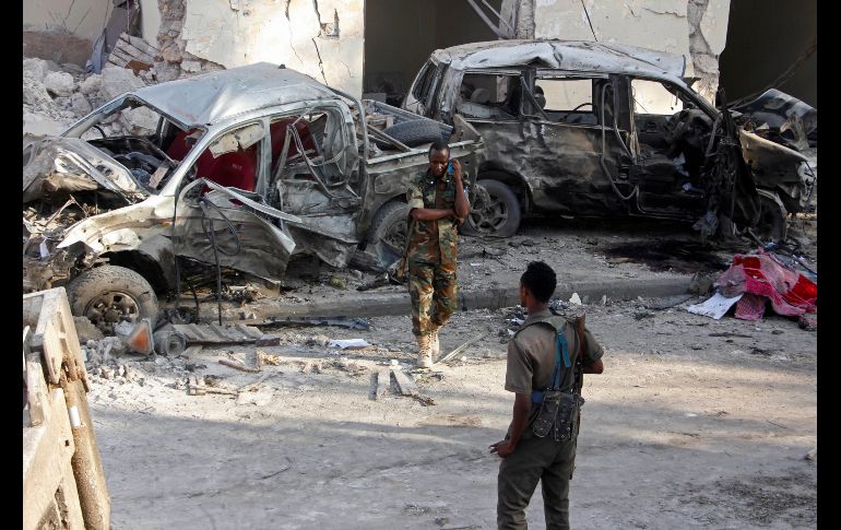 Soldados somalíes vigilan junto a automóviles destruidos en Mogadiscio, luego de la explosión de un coche bomba la víspera. El ataque, reivindicado por islamistas de Al Shabab, ha dejado 27 muertos. AP/F. Abdi Warsameh
