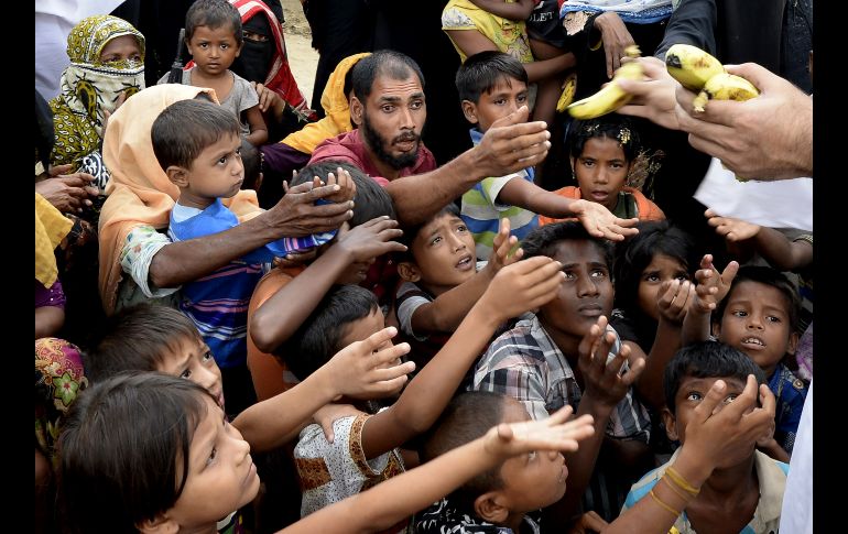 Un voluntario da plátanos a refugiados rohinyás que acaban de llegar a Teknaf, en Bangladesh, procedentes de Birmania. AFP/T. Mustafa