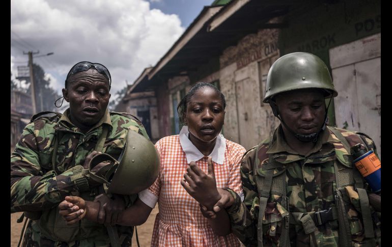 Policías ayudan a una joven que inhaló gas lacrimógeno cuando antimotines intentaban dispersar una manifestación a favor de un líder opositor en Nairobi, Kenia. AFP/F. Lerneryd