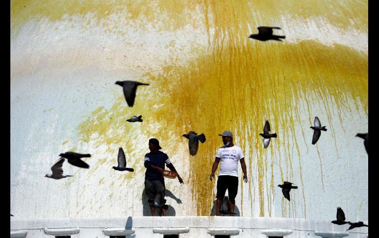 Palomas vuelan junto a trabajadores que arrojan color en la estupa Boudhanath de Katmandú, Nepal, como parte de un ritual. AP/N. Shrestha