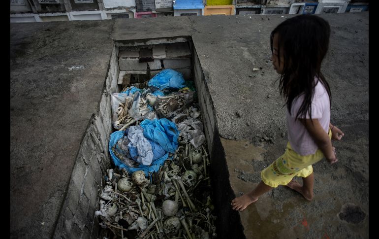 Una niña camina cerca de huesos en tumbas apiladas en el cementerio público Navotas en Manila. Millones de filipinos recuerdan a sus seres queridos fallecidos y les ofrecen flores, velas y oraciones. AFP/N. Celis