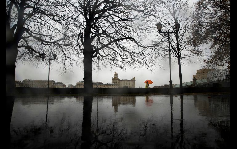 Una mujer camina en un parque de Moscú mientras llueve. AP/P. Golovkin