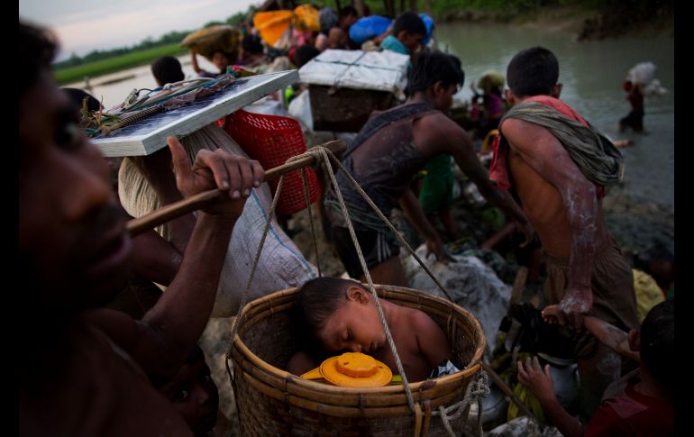 Un niño dormido es trasladado en una canasta a Palong Khali, Bangladesh, con un grupo que huye de Brimania. Unos dos mil rohinyás cruzaron hoy el río Naf y aguardaban permiso para entrar a Bangladesh. AP/B. Armangue